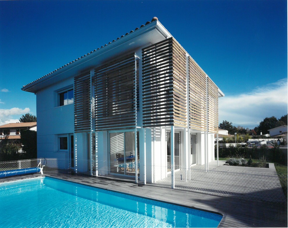 Diseño de fachada de casa blanca actual de tamaño medio de dos plantas con tejado de teja de barro, revestimiento de ladrillo y tejado a cuatro aguas