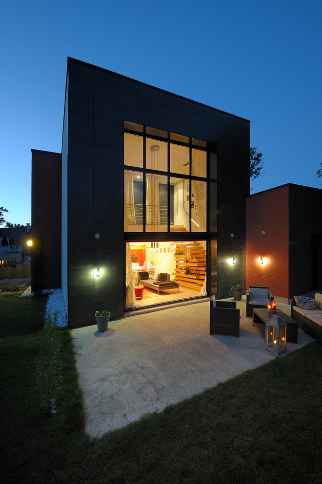 Cette image montre une façade de maison grise design de taille moyenne et à un étage avec un toit plat.