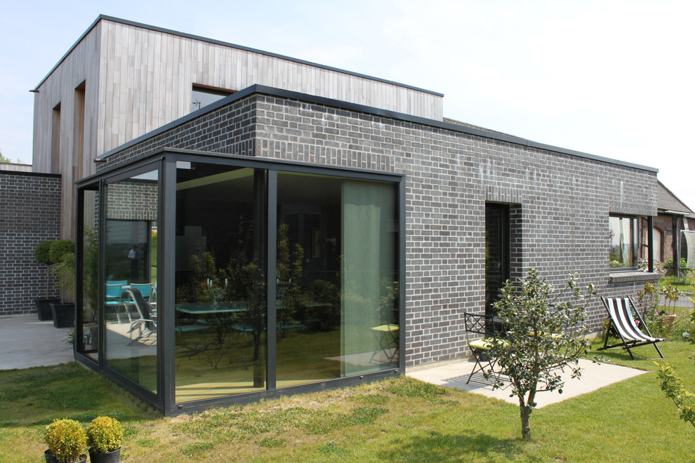 Inspiration för ett mellanstort funkis grått hus, med tegel och platt tak