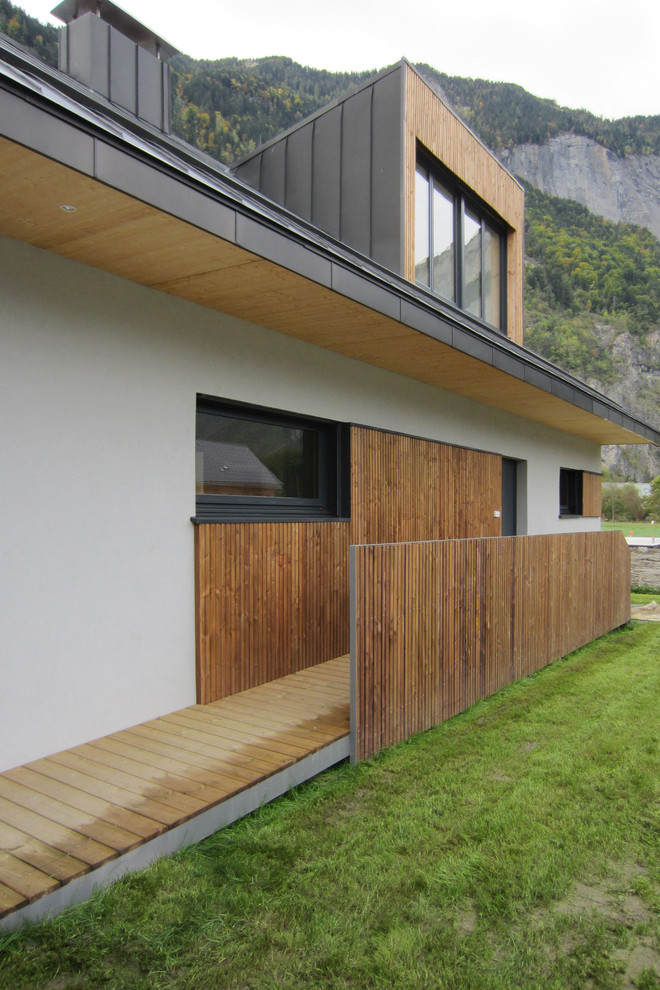 This is an example of a medium sized and white modern two floor house exterior in Grenoble with mixed cladding and a pitched roof.