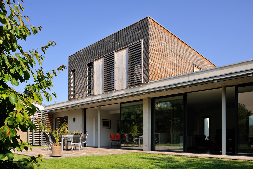 Cette photo montre une grande façade de maison tendance en bois à un étage avec un toit plat.