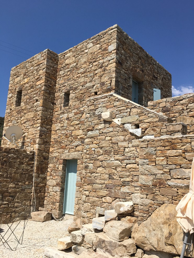 Photo of an expansive and beige mediterranean two floor detached house in Other with stone cladding.