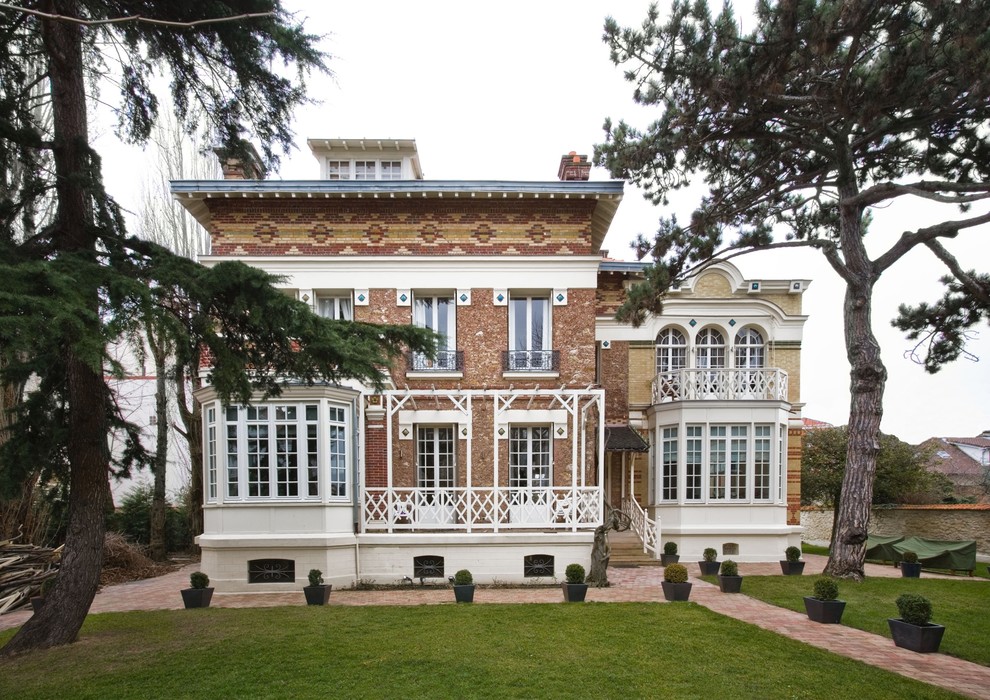 Cette image montre une façade de maison beige traditionnelle à deux étages et plus et de taille moyenne avec un revêtement mixte et un toit à deux pans.