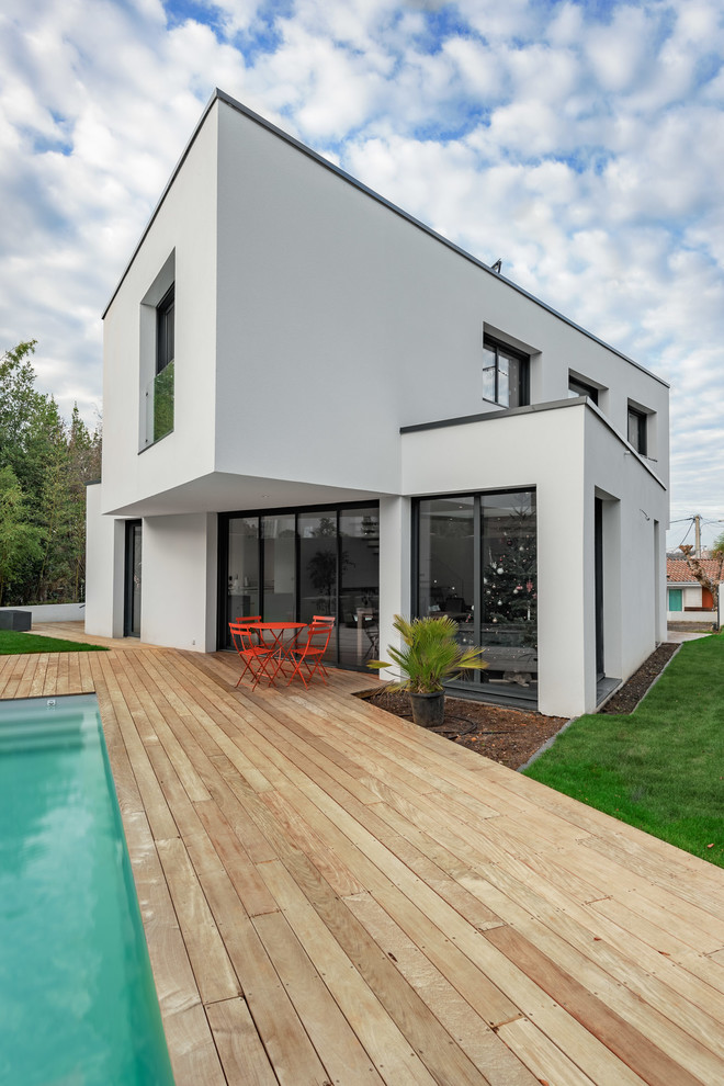 Cette image montre une façade de maison blanche minimaliste à un étage avec un toit plat.