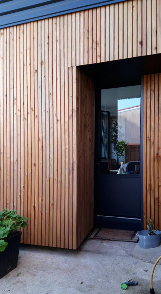 Medium sized and black contemporary two floor terraced house in Nantes with wood cladding, a butterfly roof, a tiled roof, a red roof and shiplap cladding.