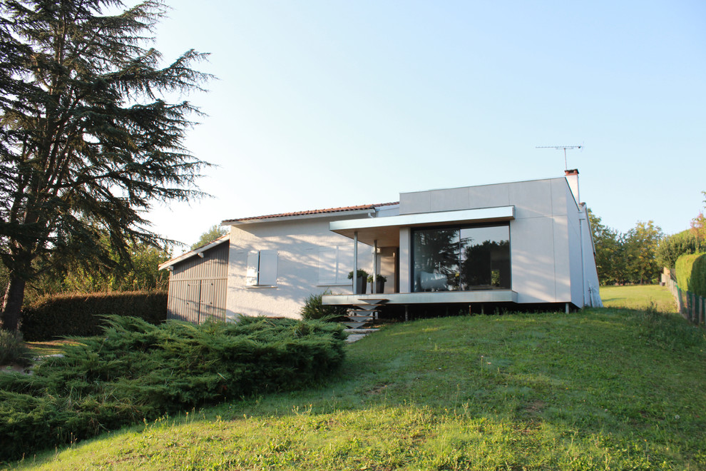 Réalisation d'une façade de maison beige design en panneau de béton fibré de taille moyenne et à un étage avec un toit plat.