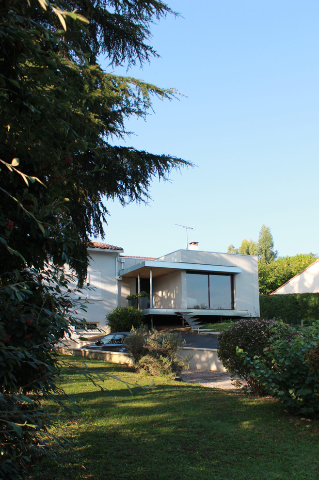 Réalisation d'une façade de maison beige design en panneau de béton fibré de taille moyenne et à un étage avec un toit plat.