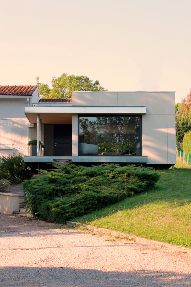 Cette photo montre une façade de maison beige tendance en panneau de béton fibré de taille moyenne et à un étage avec un toit plat.
