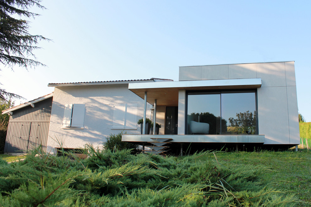 Idée de décoration pour une façade de maison beige design en panneau de béton fibré de taille moyenne et à un étage avec un toit plat.