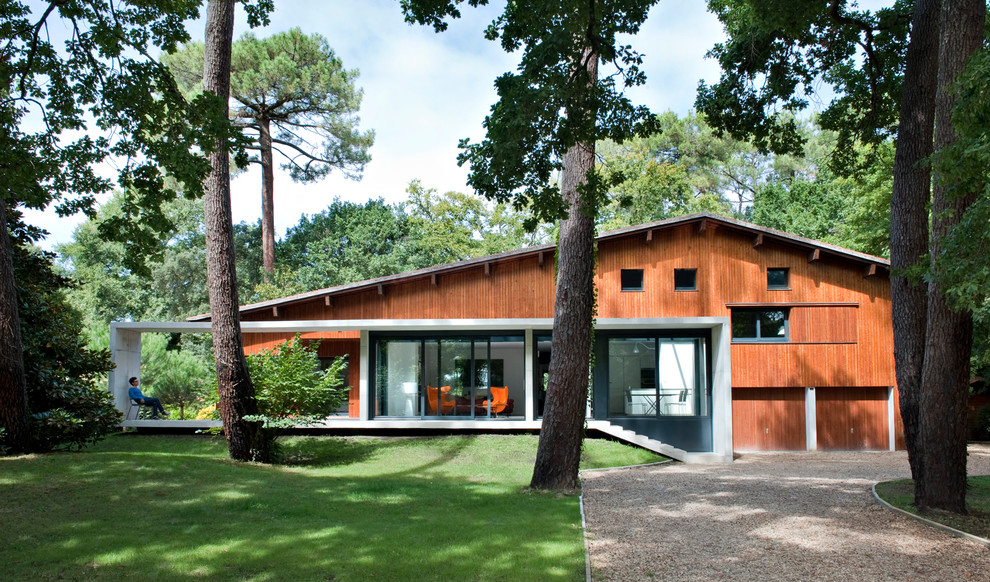 Imagen de fachada marrón actual grande de dos plantas con revestimiento de madera y tejado a dos aguas