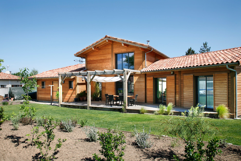 Ejemplo de fachada marrón rural de tamaño medio de dos plantas con revestimiento de madera y tejado a dos aguas