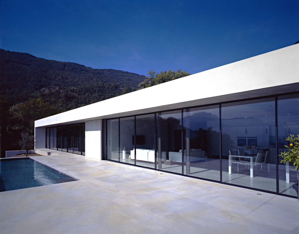 Esempio della facciata di una casa grande bianca moderna a un piano con rivestimento in vetro e tetto piano