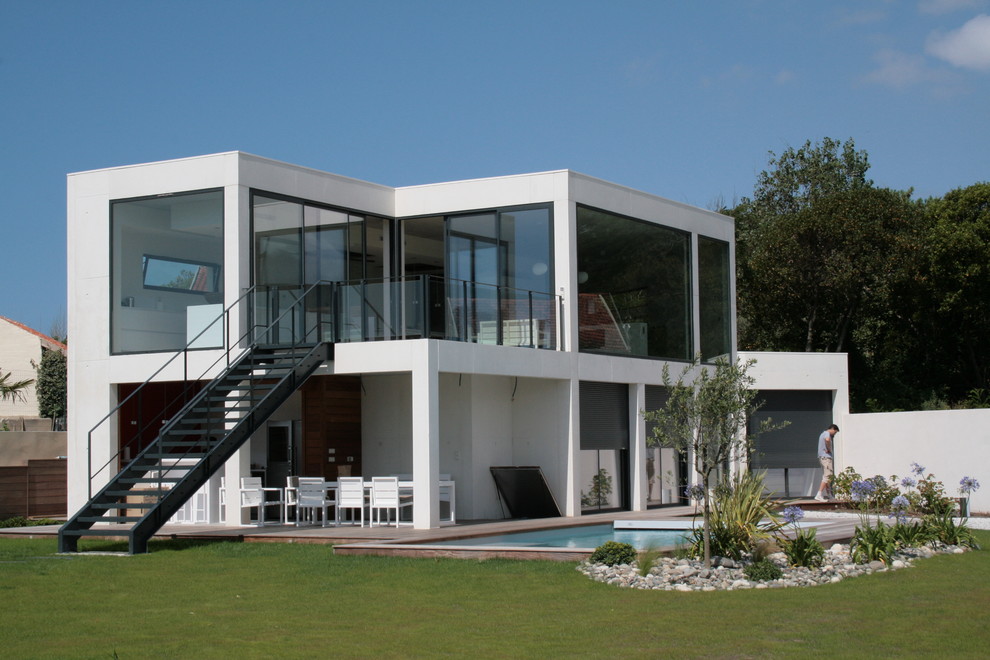 На фото: двухэтажный, белый, большой вилла в стиле модернизм с плоской крышей и крышей из смешанных материалов