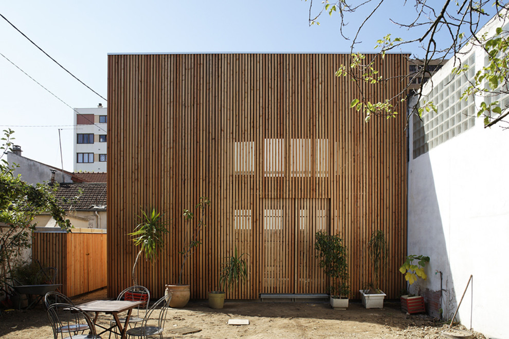 Cette image montre une façade de maison marron design en bois de taille moyenne et à un étage avec un toit plat.