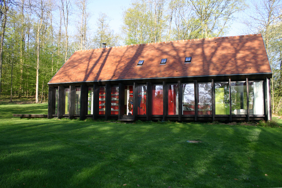 Réalisation d'une façade de maison design en verre de taille moyenne et à un étage avec un toit à deux pans.