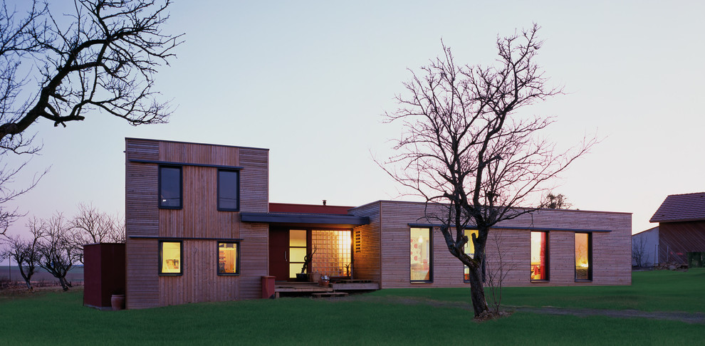 Cette photo montre une grande façade de maison marron tendance en bois à un étage avec un toit plat.