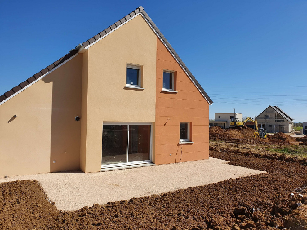 Medium sized modern detached house in Dijon with three floors, an orange house, a pitched roof and a tiled roof.