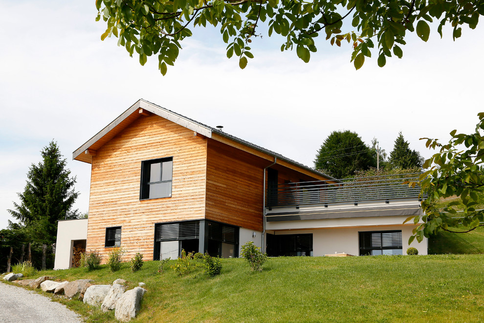 Medium sized contemporary split-level house exterior in Grenoble with wood cladding and a pitched roof.