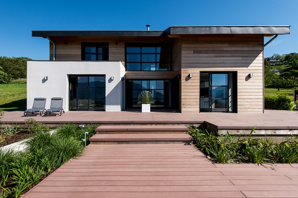 Exemple d'une grande façade de maison marron tendance à un étage avec un revêtement mixte et un toit plat.