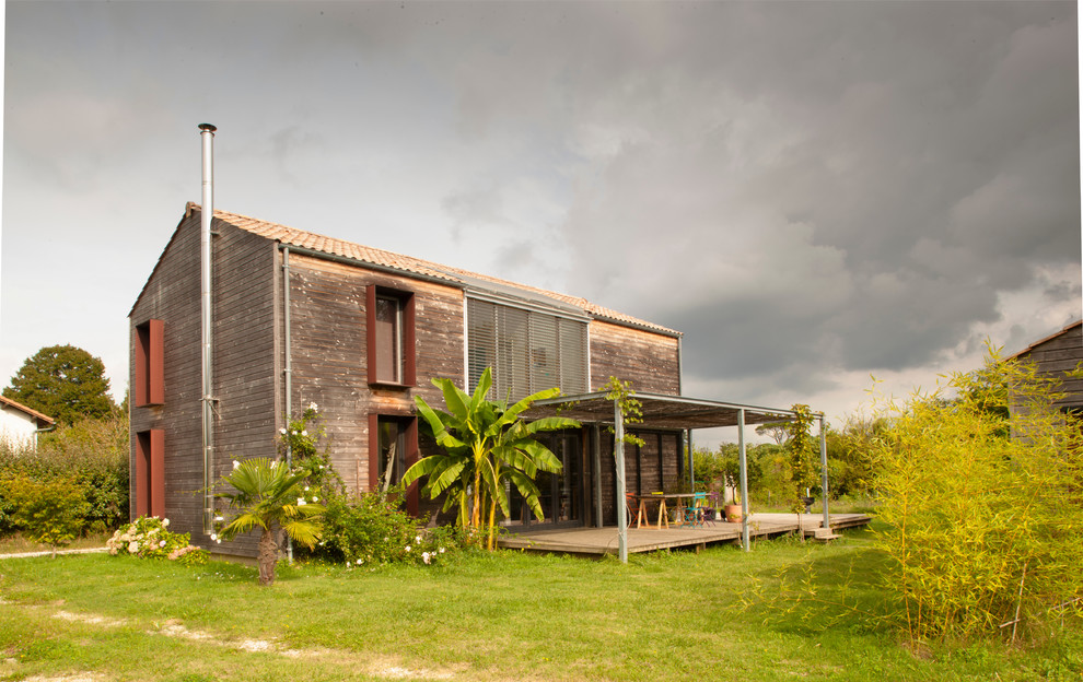 Imagen de fachada tropical de tamaño medio con tejado a dos aguas y revestimiento de madera