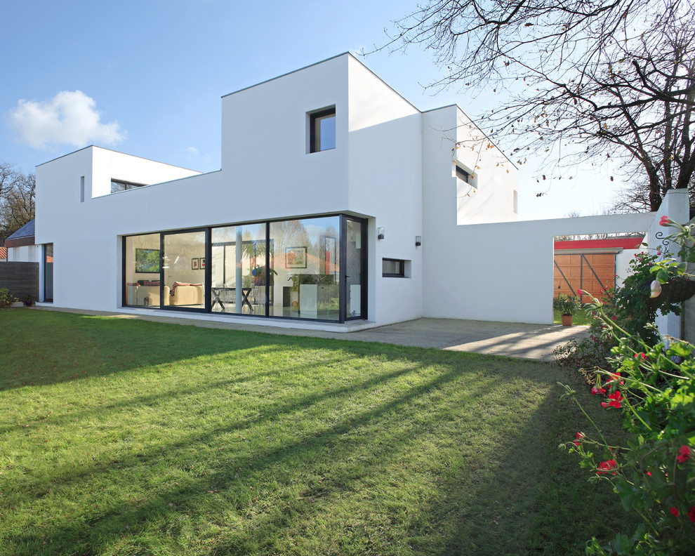 Idée de décoration pour une façade de maison blanche design en stuc à un étage avec un toit plat.
