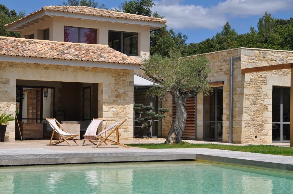 Стильный дизайн: двухэтажный, бежевый дом в средиземноморском стиле с облицовкой из камня - последний тренд