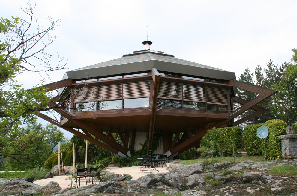 Cette image montre une grande façade de maison marron design à un étage avec un revêtement mixte et un toit à quatre pans.