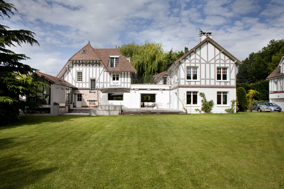 Foto della villa ampia bianca classica a due piani con falda a timpano, copertura in tegole e tetto marrone