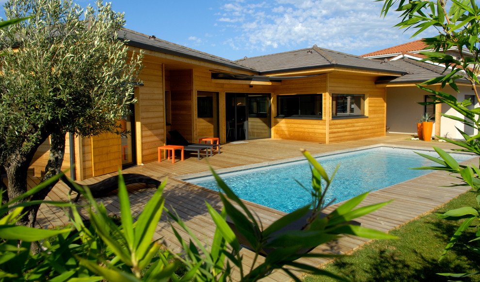 Cette photo montre une façade de maison marron tendance en bois de taille moyenne et de plain-pied avec un toit à quatre pans.