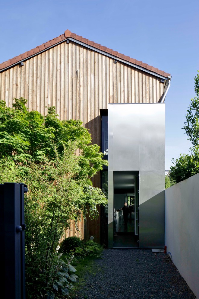 Foto della facciata di una casa contemporanea a due piani con rivestimenti misti e tetto a capanna
