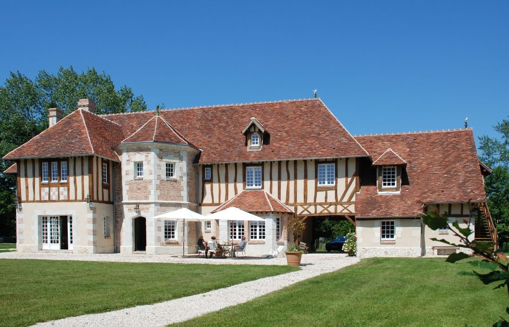 Immagine della facciata di una casa grande beige country a tre piani con rivestimenti misti e tetto a padiglione