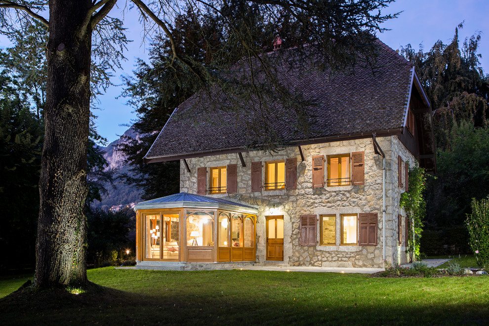 Diseño de fachada beige de estilo de casa de campo grande de tres plantas con revestimiento de piedra y tejado a la holandesa
