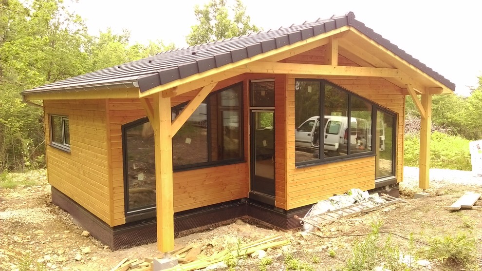 Diseño de fachada de casa beige contemporánea pequeña de una planta con revestimiento de madera, tejado a dos aguas y tejado de teja de barro