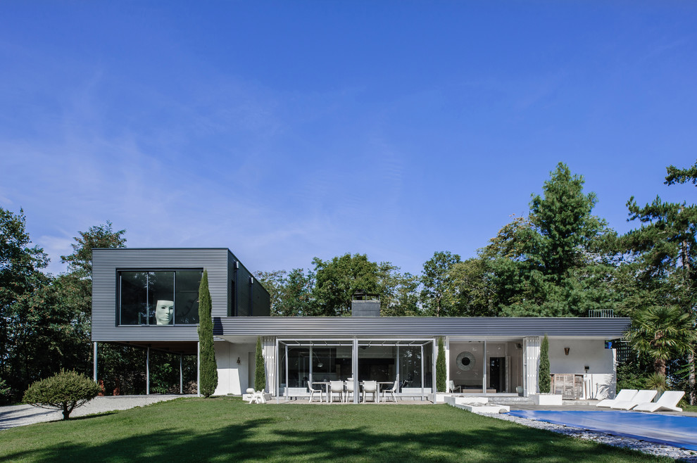 Idée de décoration pour une façade de petite villa blanche minimaliste à niveaux décalés avec un revêtement mixte et un toit plat.