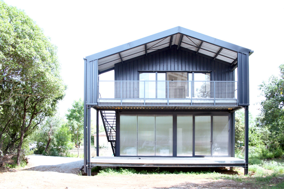 Diseño de fachada de casa gris industrial de tamaño medio de dos plantas con revestimiento de metal, tejado a dos aguas y tejado de metal