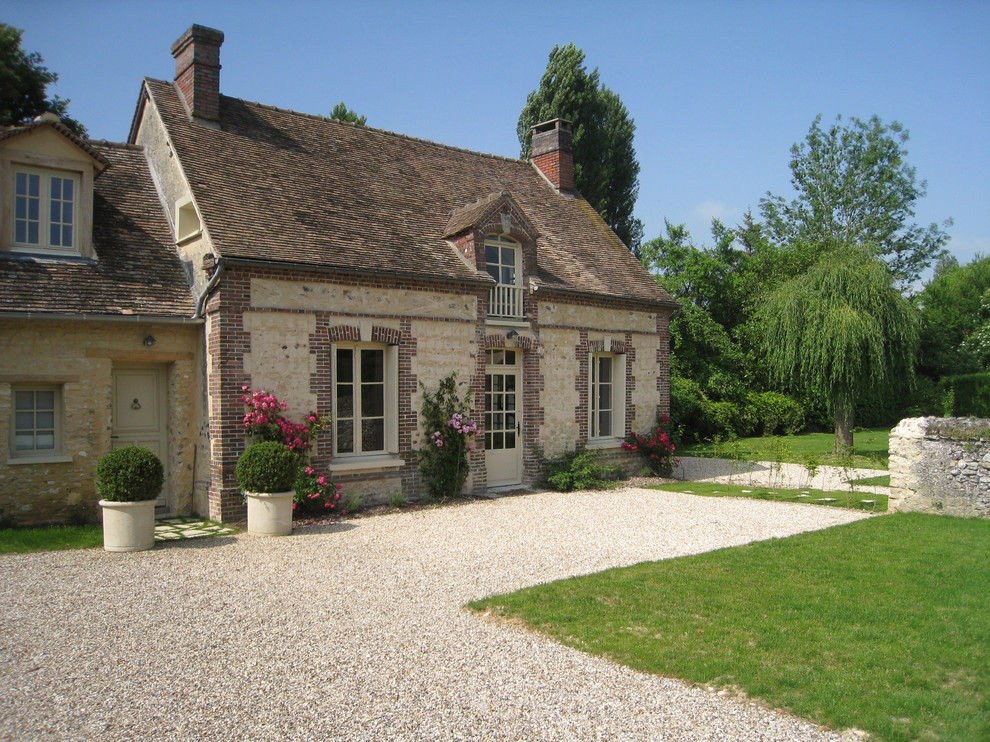Mid-sized traditional beige two-story brick gable roof idea in Paris
