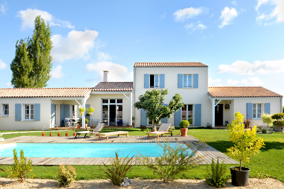 Cette photo montre une grande façade de maison beige méditerranéenne à un étage avec un toit à deux pans.