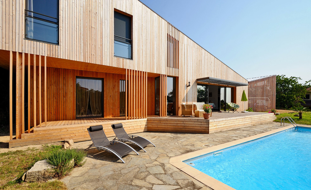 Cette photo montre une façade de maison marron tendance en bois de taille moyenne et à un étage avec un toit en appentis.