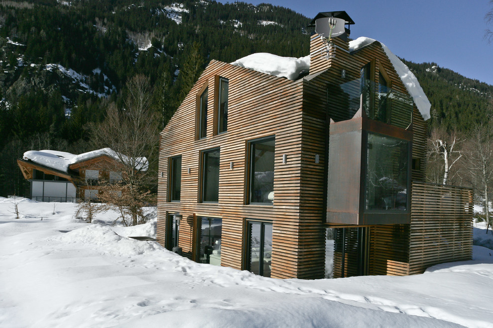 Modelo de fachada marrón actual de tamaño medio de dos plantas con revestimiento de madera y tejado a dos aguas