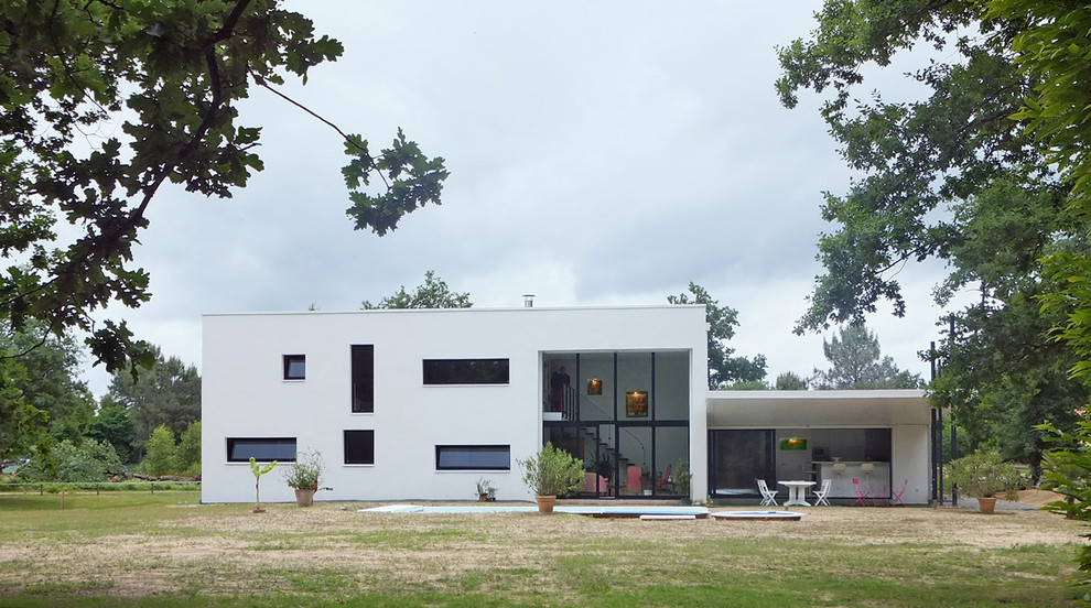 Idée de décoration pour une façade de petite villa blanche minimaliste de taille moyenne et à un étage avec un toit plat.