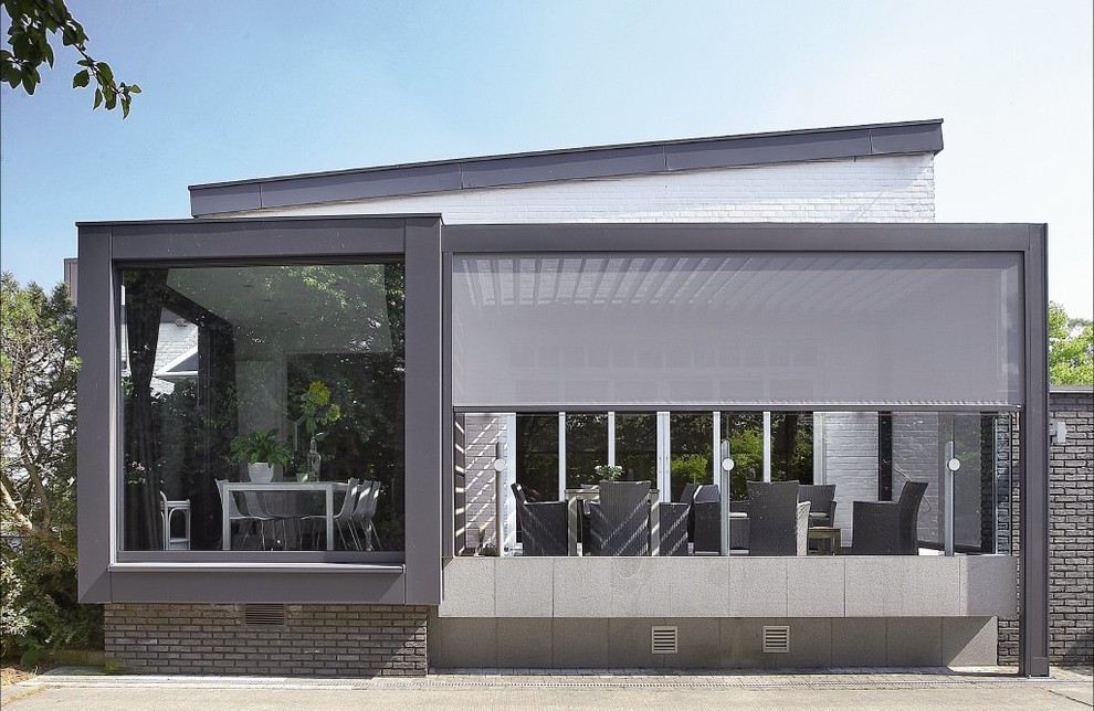 Idée de décoration pour une façade de petite villa grise minimaliste en brique de taille moyenne et à un étage avec un toit en appentis.