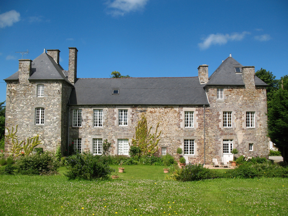 Immagine della facciata di una casa grande grigia classica a tre piani con rivestimento in pietra e tetto a padiglione