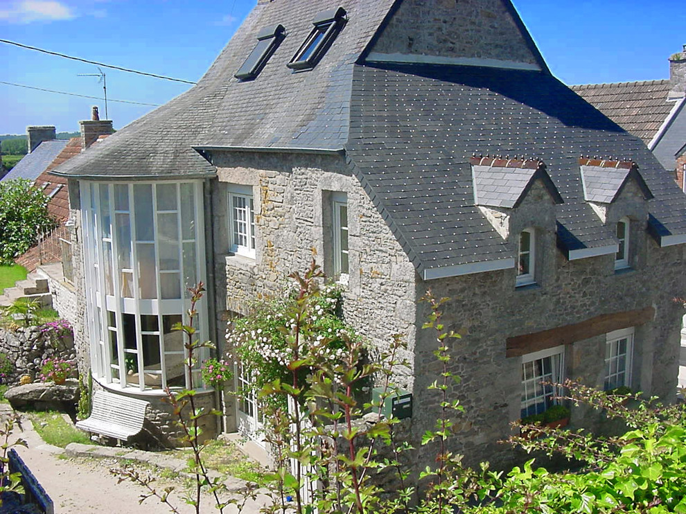 Inspiration pour une façade de maison grise traditionnelle en pierre de taille moyenne et à deux étages et plus avec un toit à quatre pans.