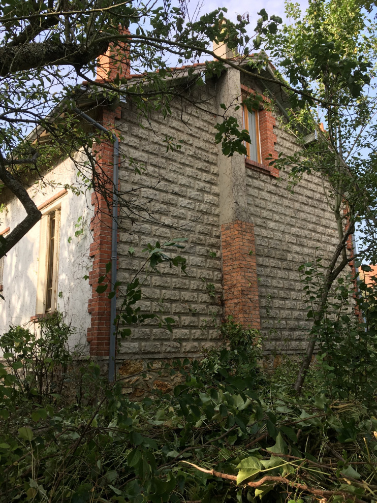 Cette photo montre une façade de maison beige chic en brique de taille moyenne et à un étage avec un toit à deux pans et un toit en tuile.