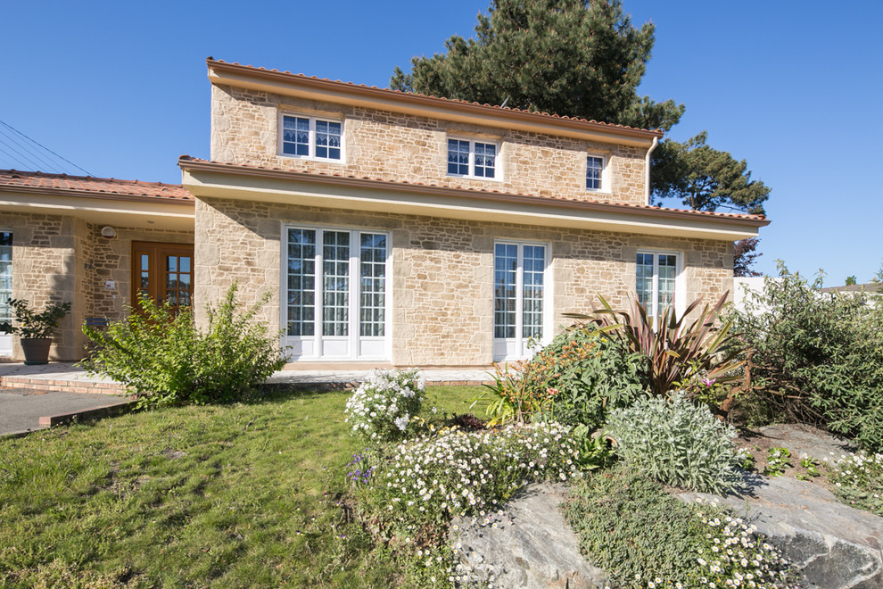 На фото: двухэтажный, бежевый дом среднего размера в средиземноморском стиле с облицовкой из камня и двускатной крышей с