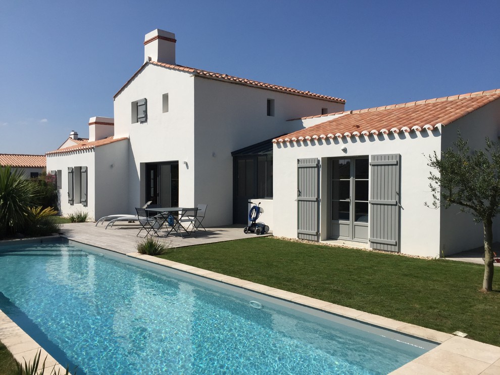 Imagen de fachada blanca mediterránea de tamaño medio de dos plantas con tejado a dos aguas