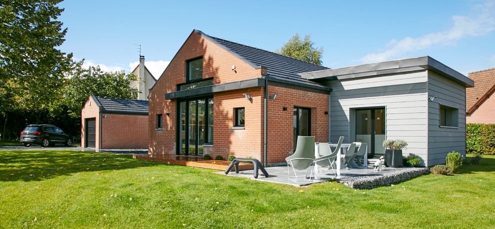 Aménagement d'une façade de maison métallique et rouge contemporaine de taille moyenne et à un étage avec un toit mixte.