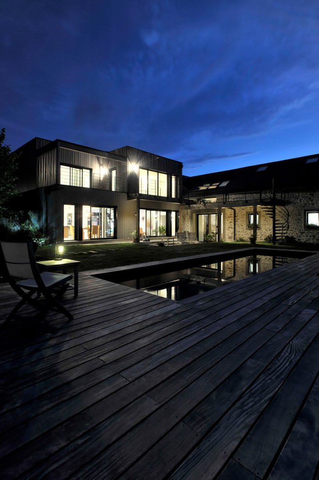 Foto della villa grande contemporanea a due piani con rivestimento in legno, tetto piano e copertura mista