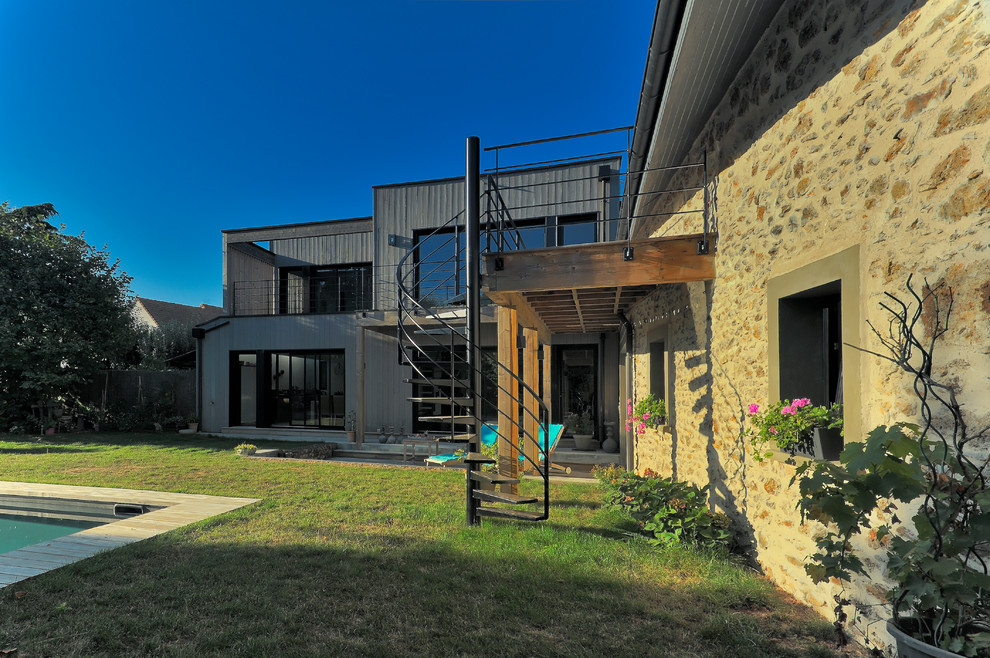 Diseño de fachada de casa contemporánea grande de dos plantas con revestimiento de madera, tejado plano y tejado de varios materiales