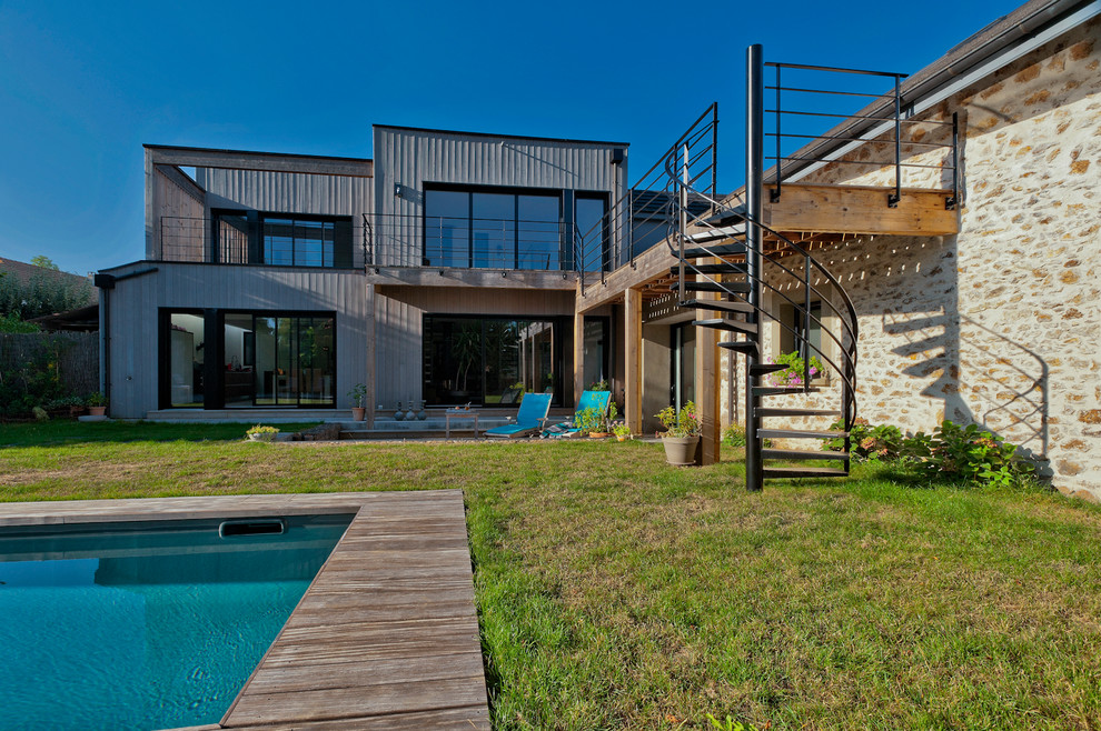 Réalisation d'une grande façade de maison grise design en bois à un étage avec un toit plat et un toit mixte.